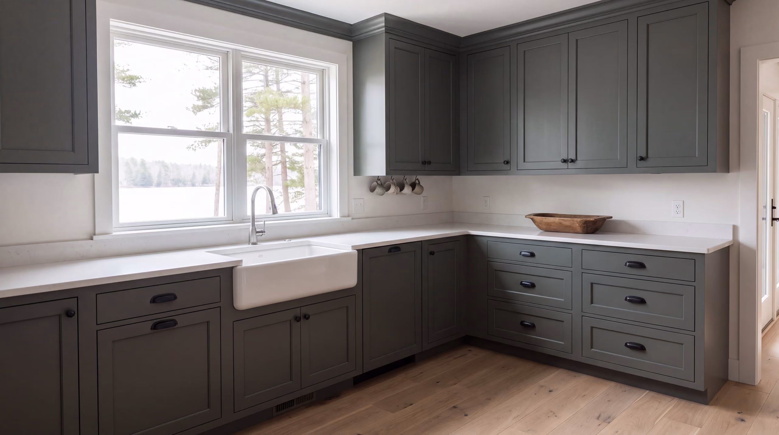 Kitchen with refinished shaker cabinets in satin green-gray enamel and brass hardware
